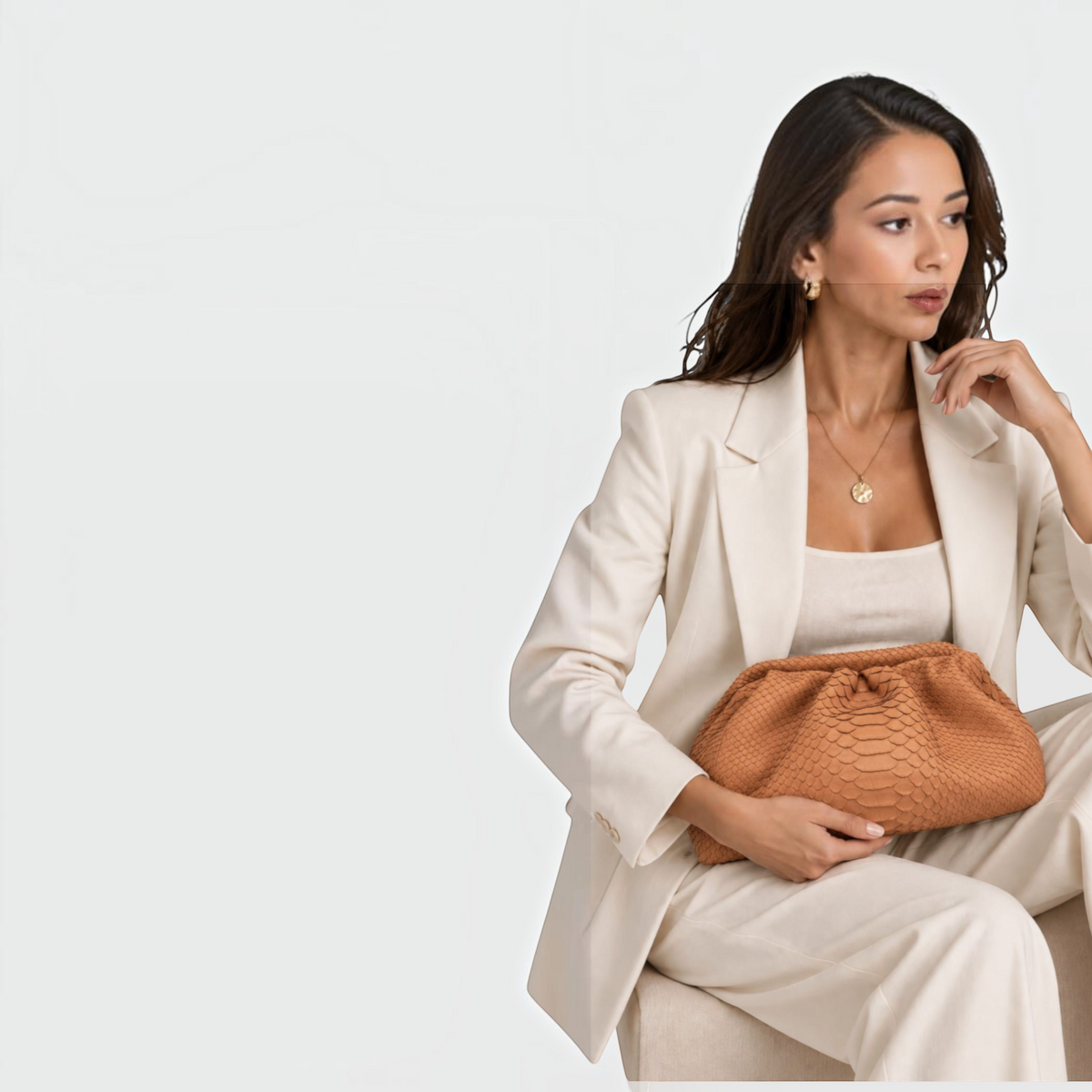 Pochette Camel PYTHON CLUTCH en cuir de python véritable avec texture écailles, tenue par une femme en tailleur blanc