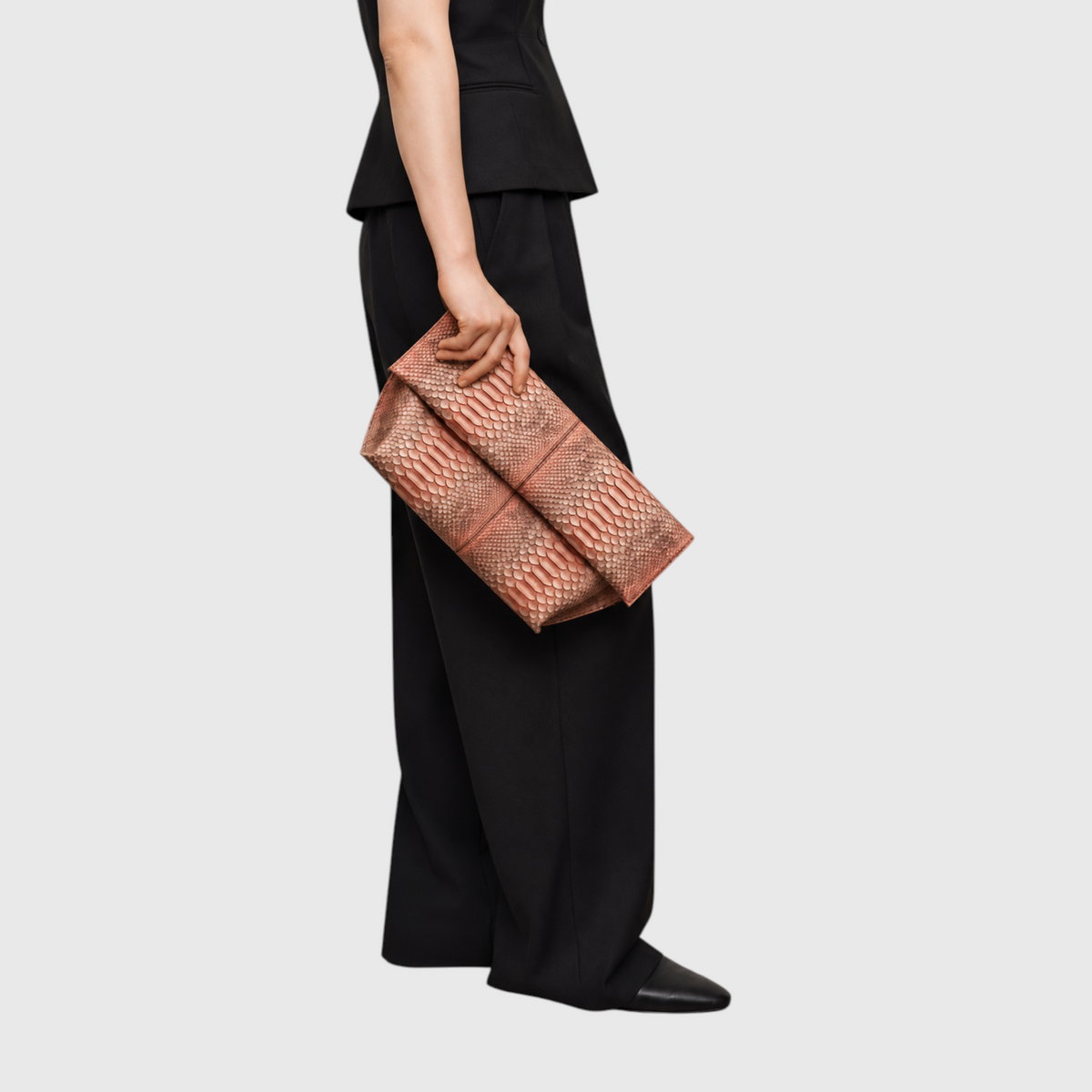 Woman carrying the copper rose genuine python leather clutch with a black outfit