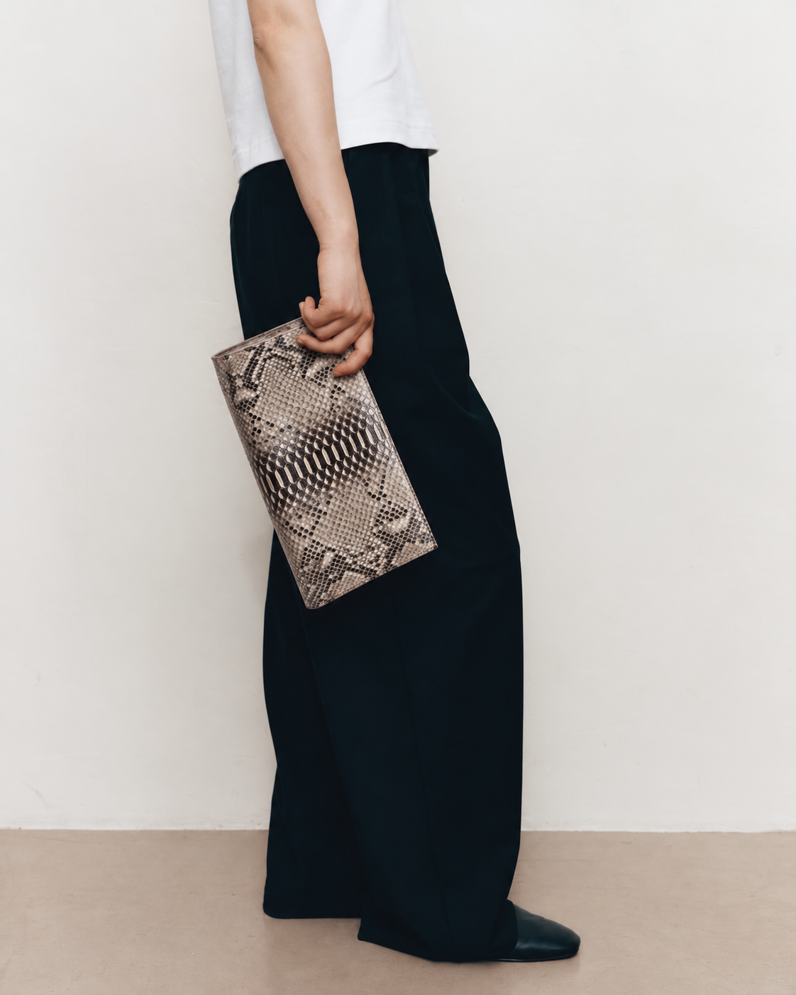 Woman carrying the Natural Taupe python clutch with minimalist clothing