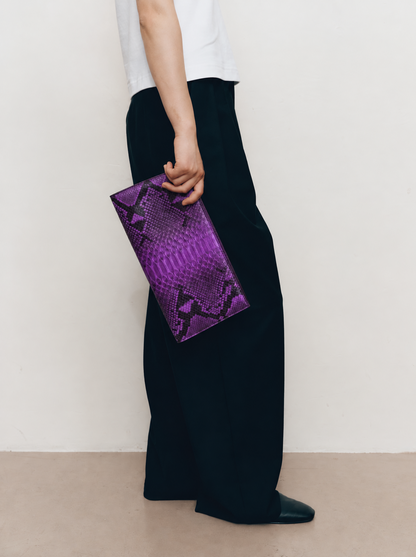 Purple python leather evening clutch held in hand