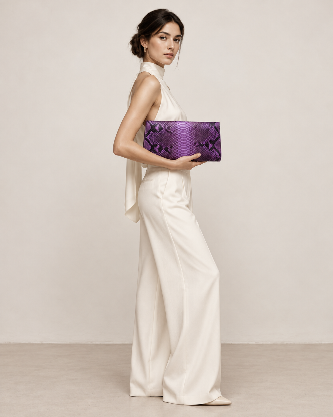 Elegant woman in an ivory outfit carrying a purple python clutch