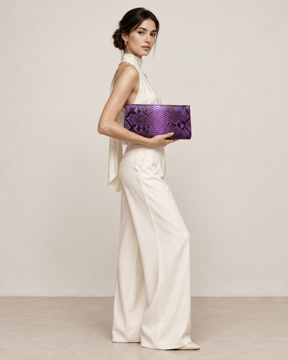 Elegant woman in an ivory outfit carrying a purple python clutch