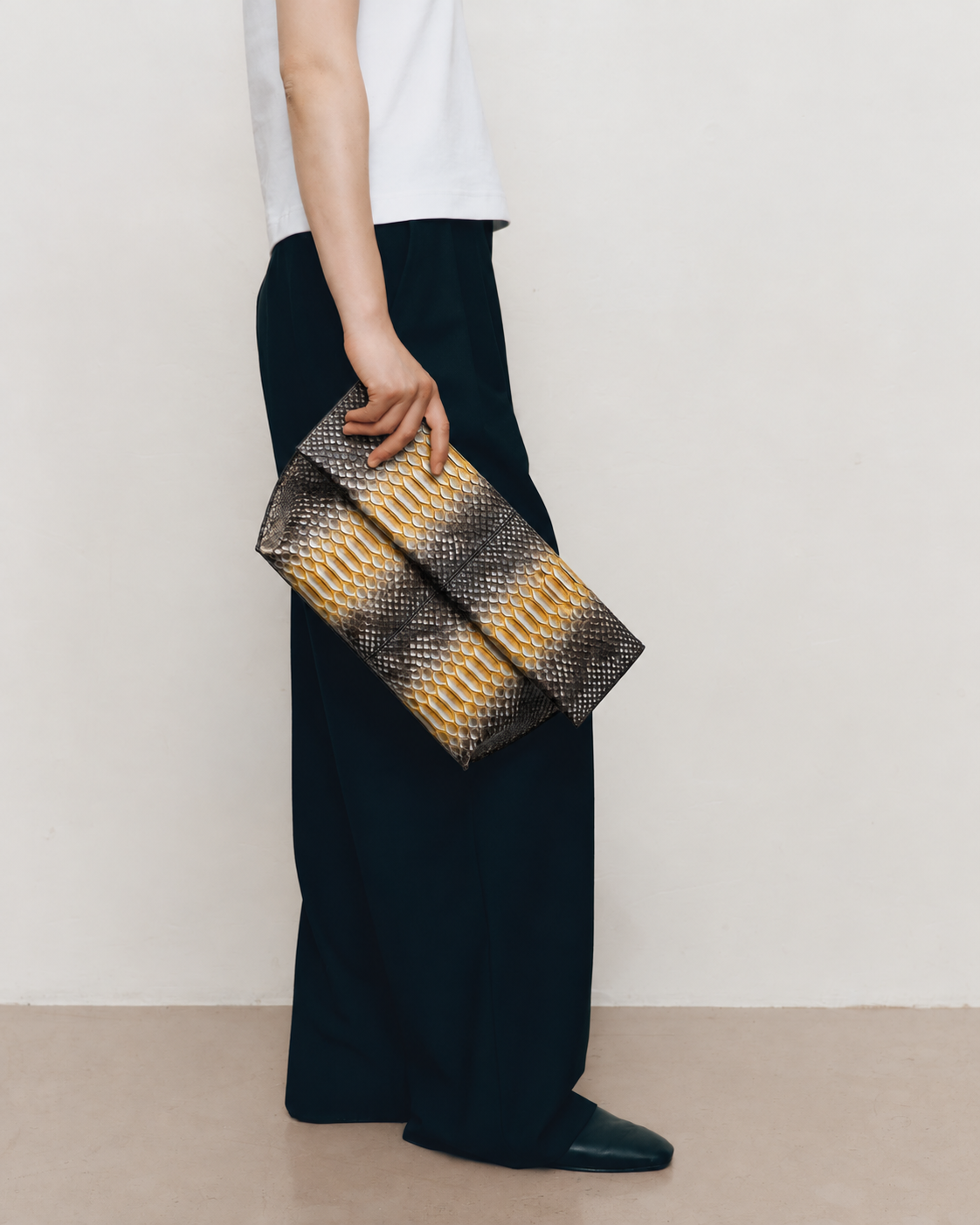 Woman carrying Honey Gold and charcoal genuine python leather foldover clutch by hand