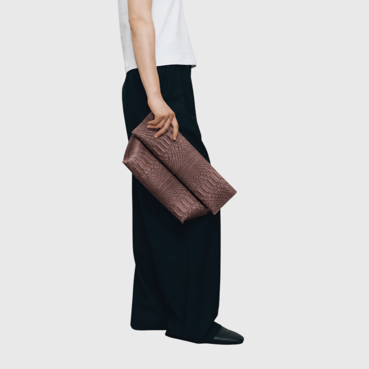 Woman carrying Smoky Taupe python leather foldover clutch by hand