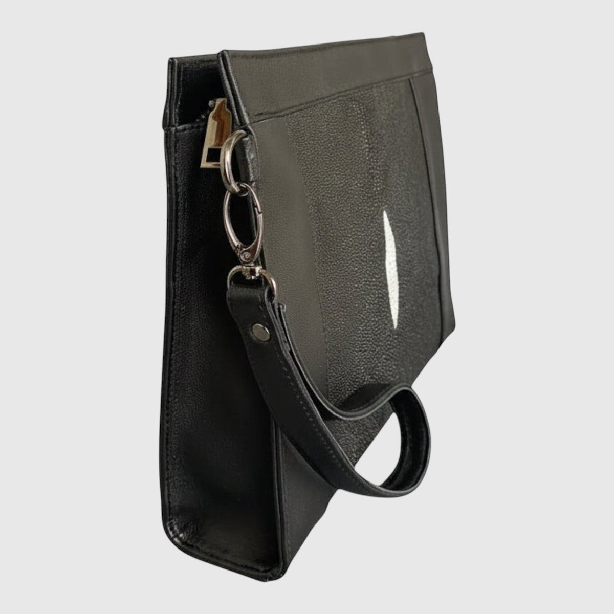 Pochette Leather craftman en cuir noir avec détail central en galuchat et dragonne amovible, vue de profil.