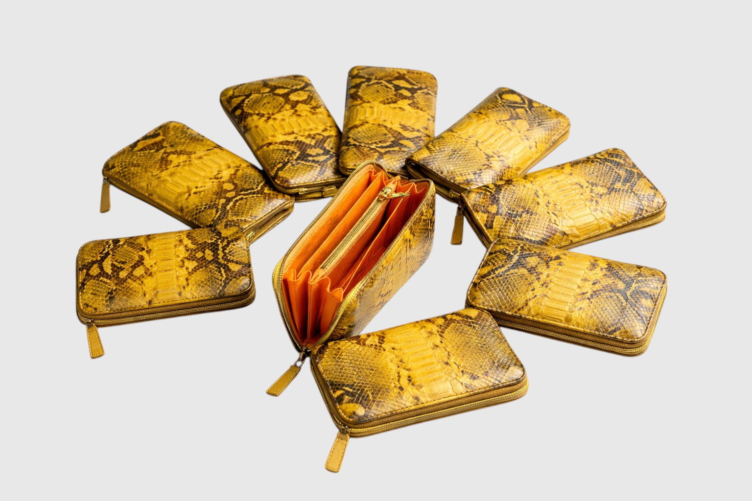 Portefeuille Leather craftman en cuir de serpent jaune avec intérieur orange, disposé en cercle sur fond blanc.