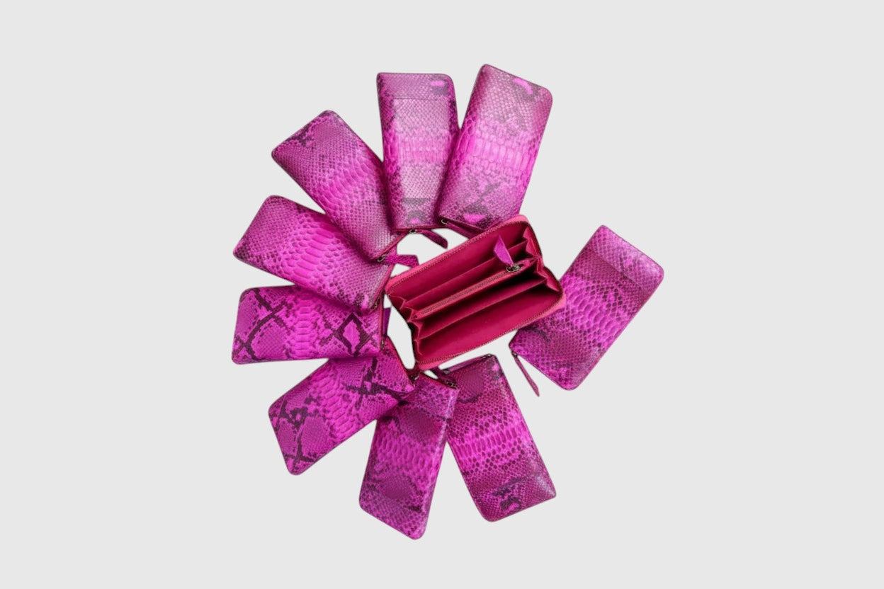 Portefeuille Leather craftman en cuir de serpent rose vif disposé en cercle avec un modèle ouvert au centre