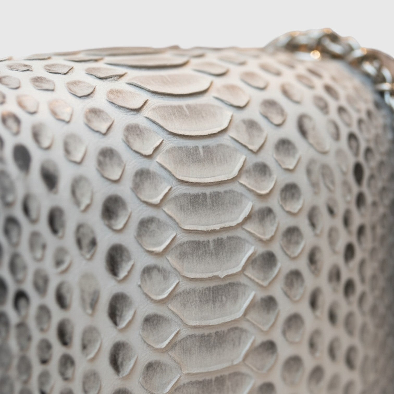 Gros plan sur le cuir gaufré python gris neutre du sac à bandoulière Leather craftman avec chaîne métallique