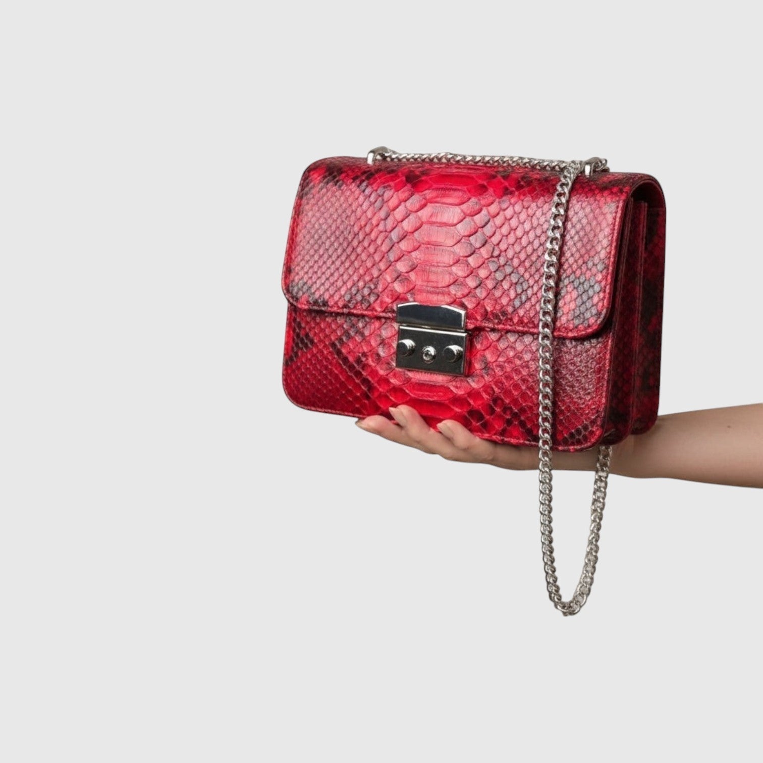 Sac à bandoulière Leather craftman en cuir rouge rubis avec texture python, chaîne métallique et fermoir sécurisé.