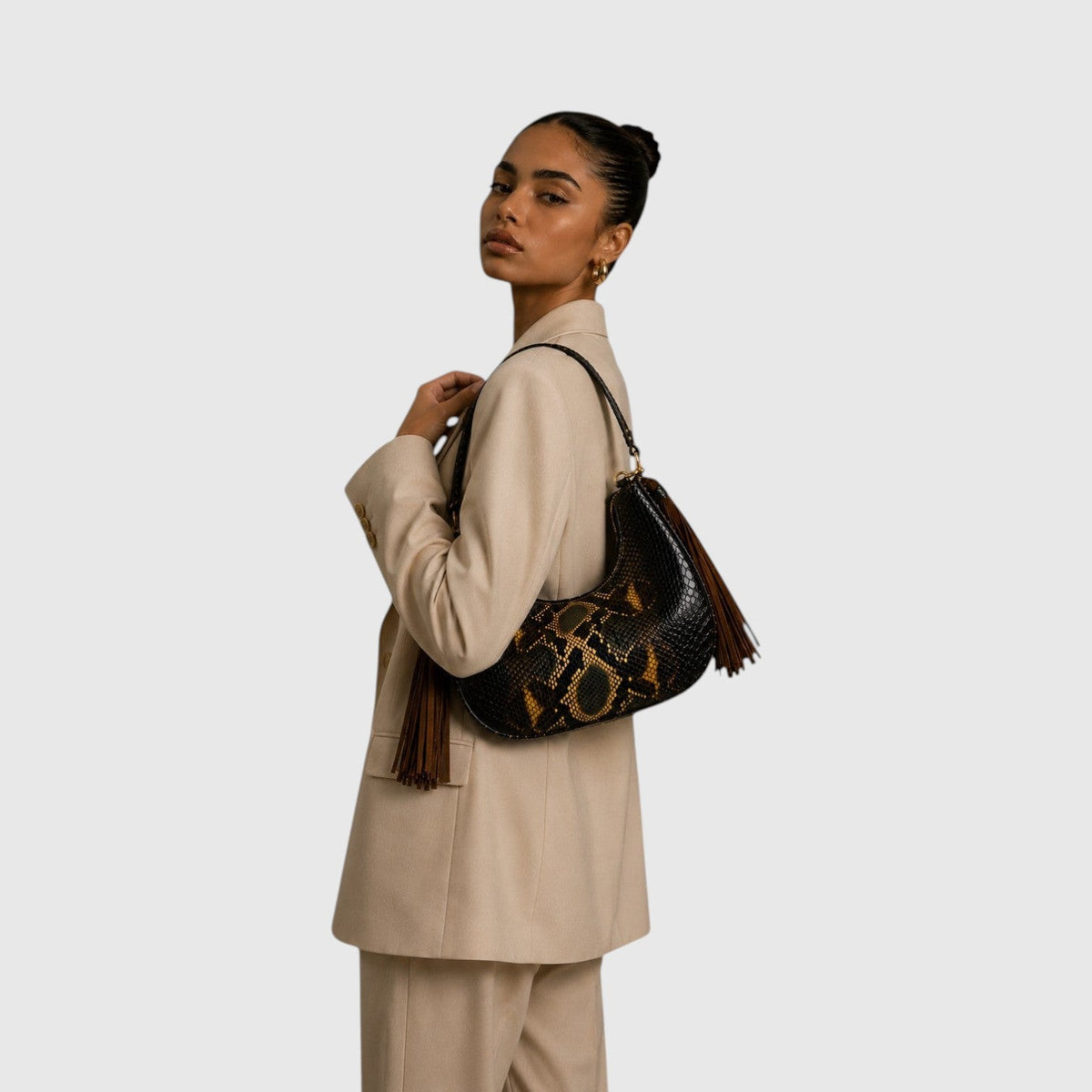 Femme portant le sac Fofana de Leather craftman en cuir de python avec pompons en daim et détails dorés