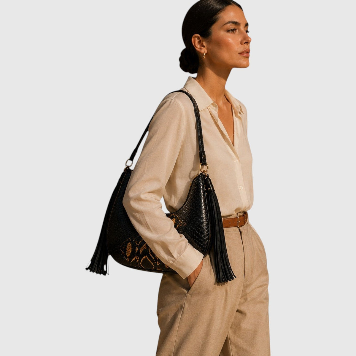 Femme portant le sac hobo Fofana de Leather craftman en cuir de python noir et doré avec pompons en daim
