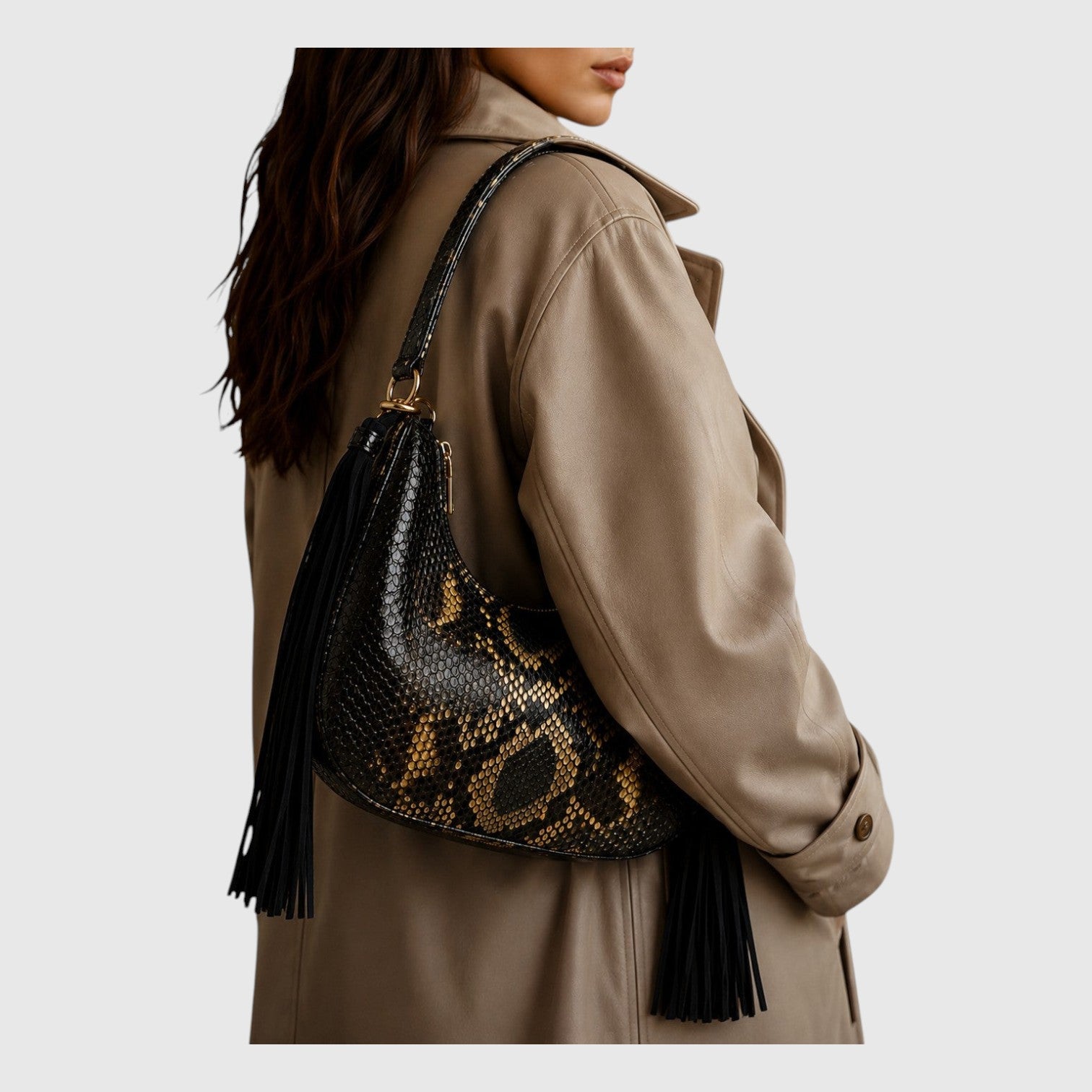 Sac hobo Fofana par Leather craftman en cuir de python noir et doré avec pompons en daim portés à l'épaule