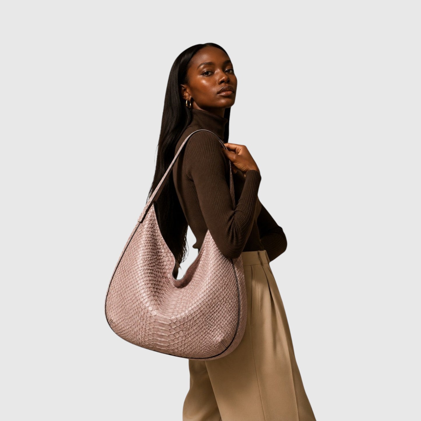 Modèle portant un sac hobo Leather craftman en cuir de python rose poudré avec une texture à écailles naturelle