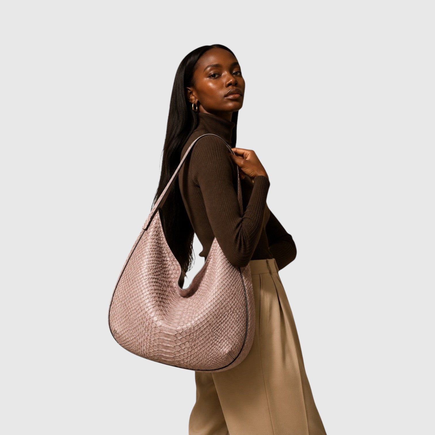 Modèle portant un sac hobo Leather craftman en cuir de python rose poudré avec une texture à écailles naturelle