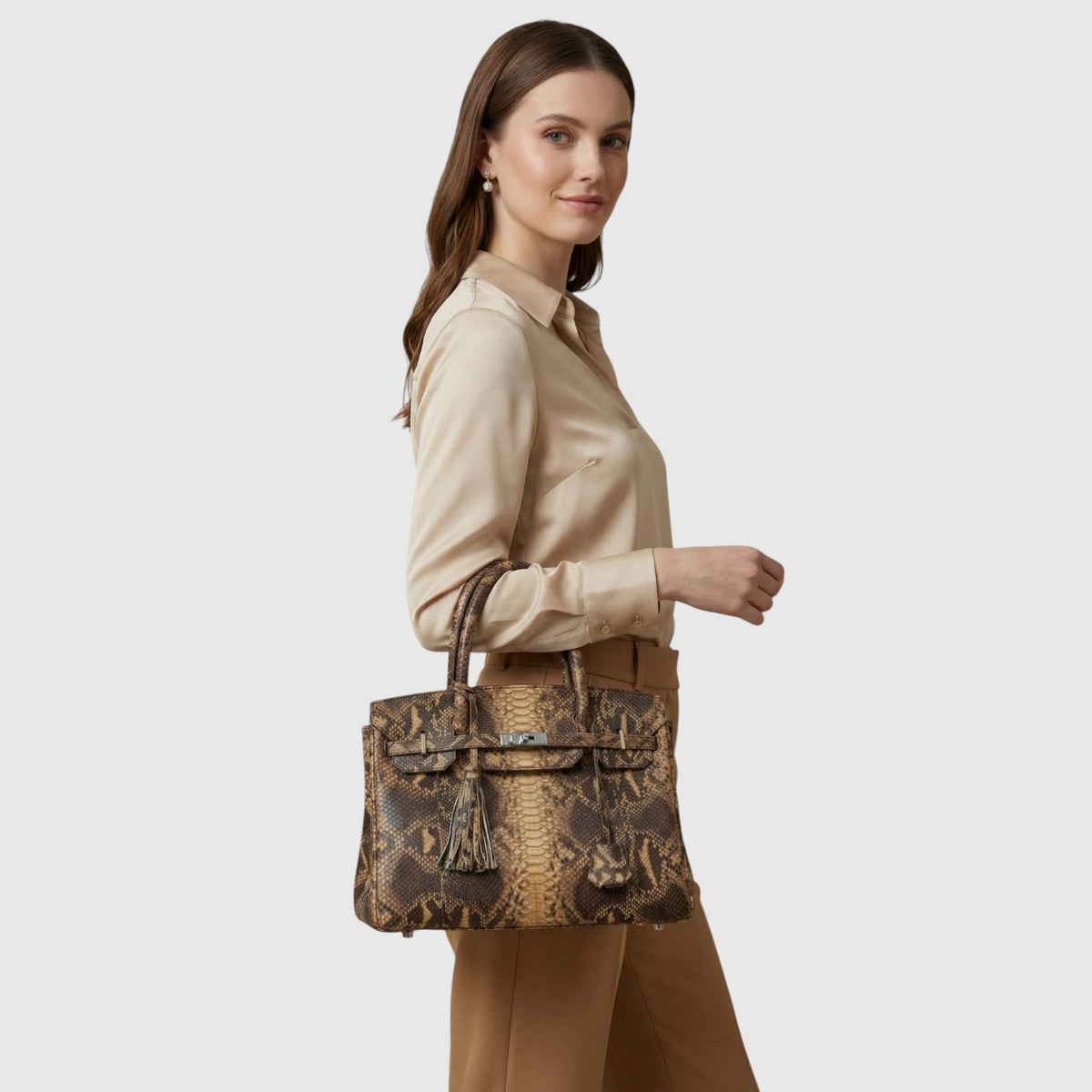 Femme portant un sac à main Leather craftman en cuir de python véritable avec détails dorés sur fond blanc