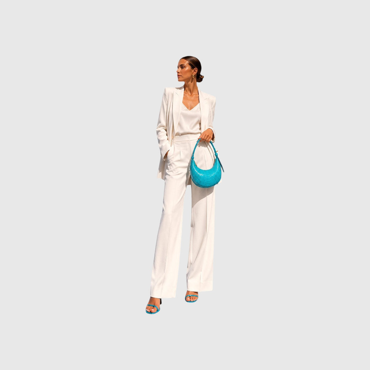 Modèle portant un sac bleu Python Icon de Leather craftman avec un ensemble tailleur blanc et des sandales assorties