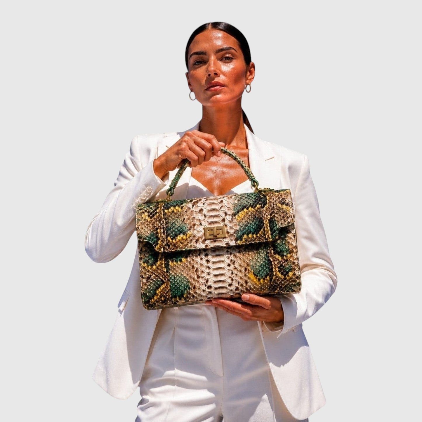 Femme en costume blanc tenant un sac à main Leather craftman en cuir de python émeraude et doré avec fermoir doré.