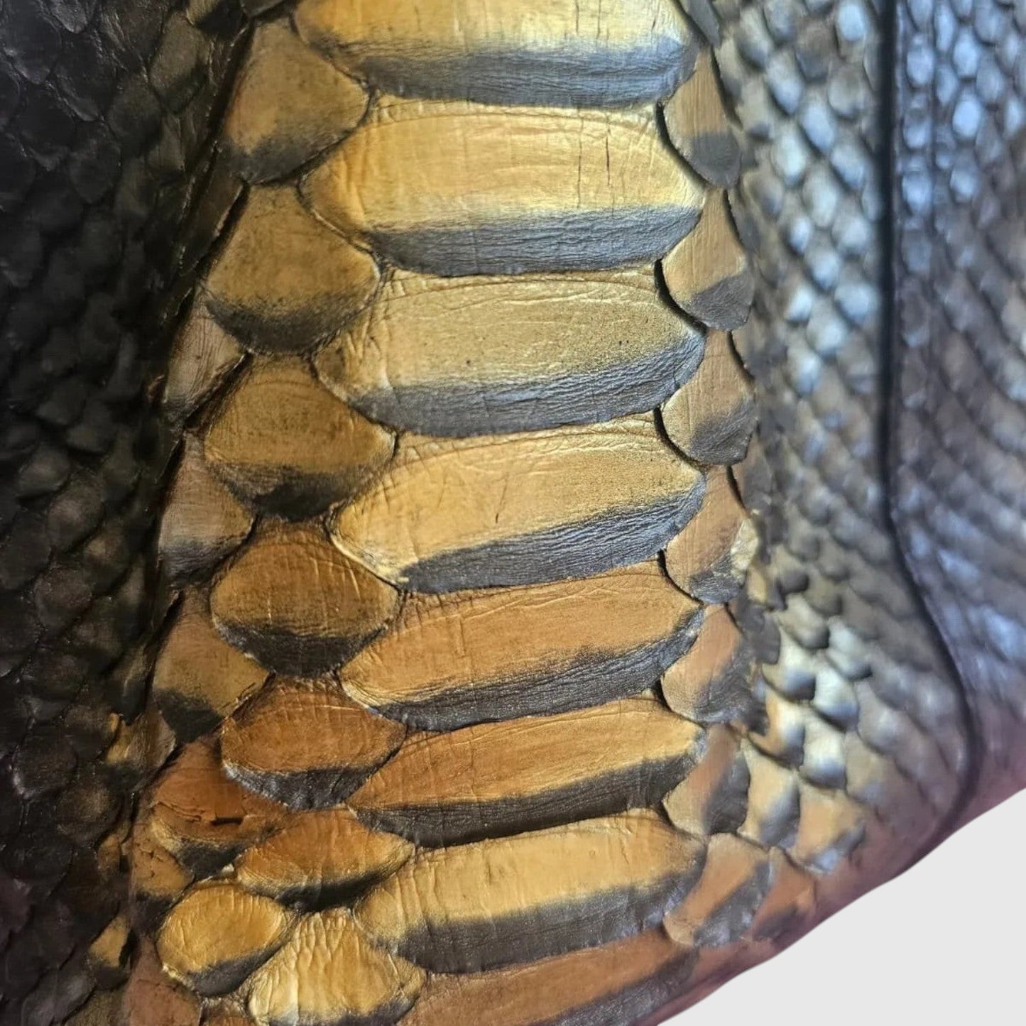 Gros plan sur le cuir de python noir et doré du sac à main Sahara Gold Python de la marque Leather craftman.