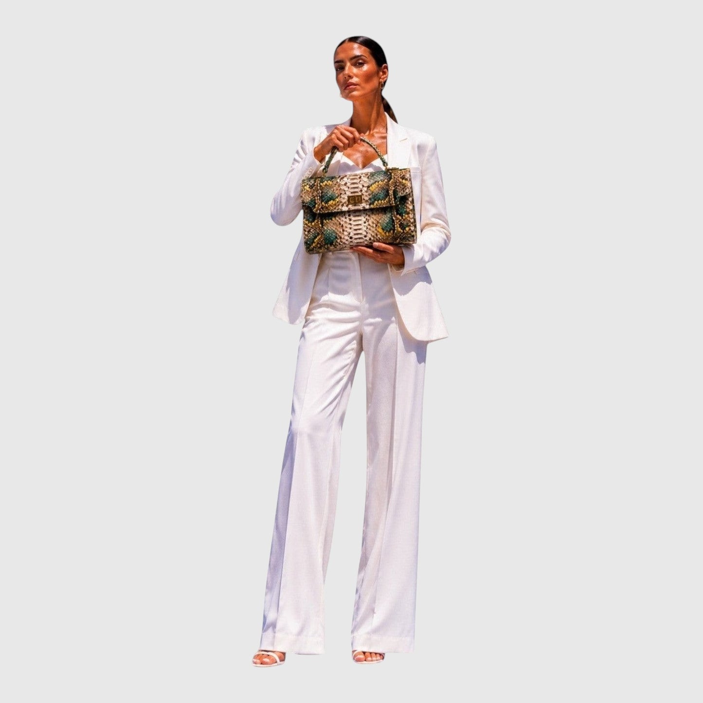 Femme en costume blanc tenant un sac à main structuré en cuir de python vert et doré Leather craftman