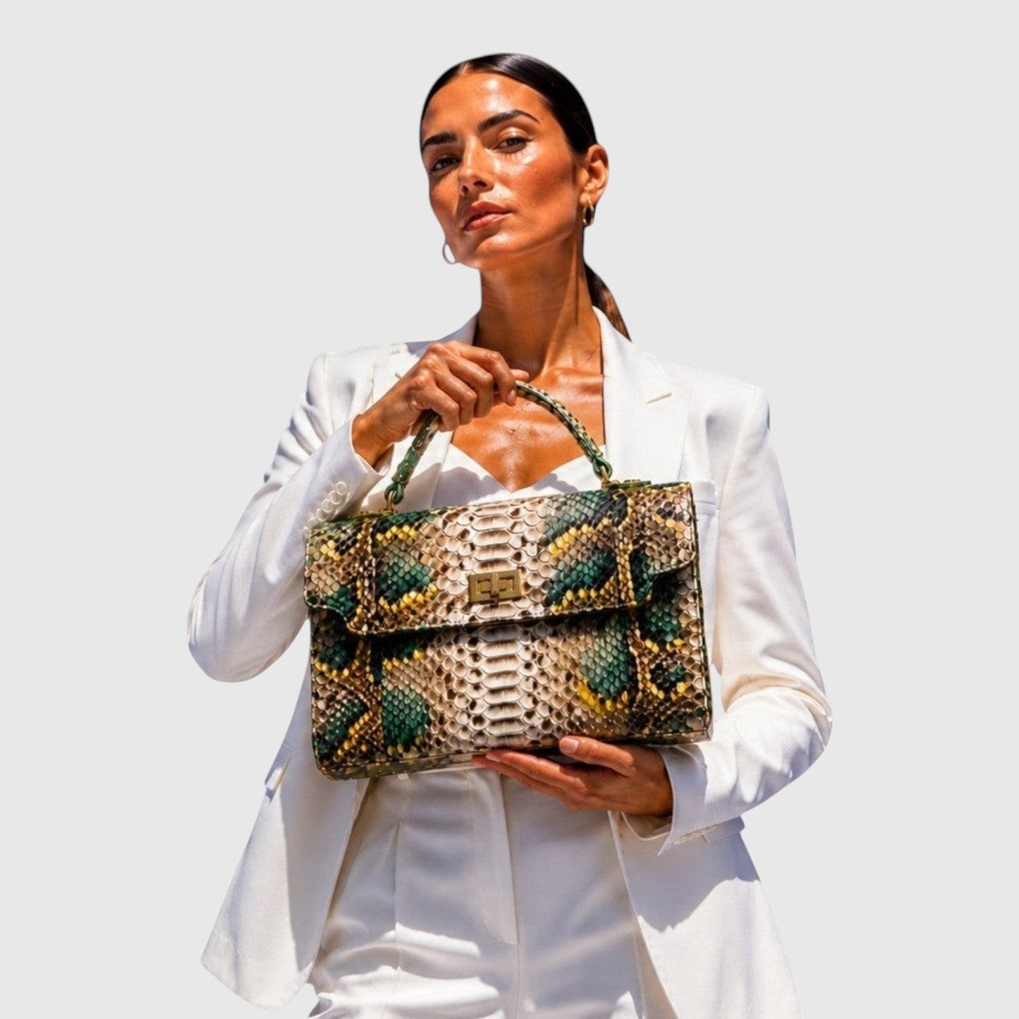 Femme en costume blanc tenant un sac à main structuré en cuir de python vert et doré de Leather craftman